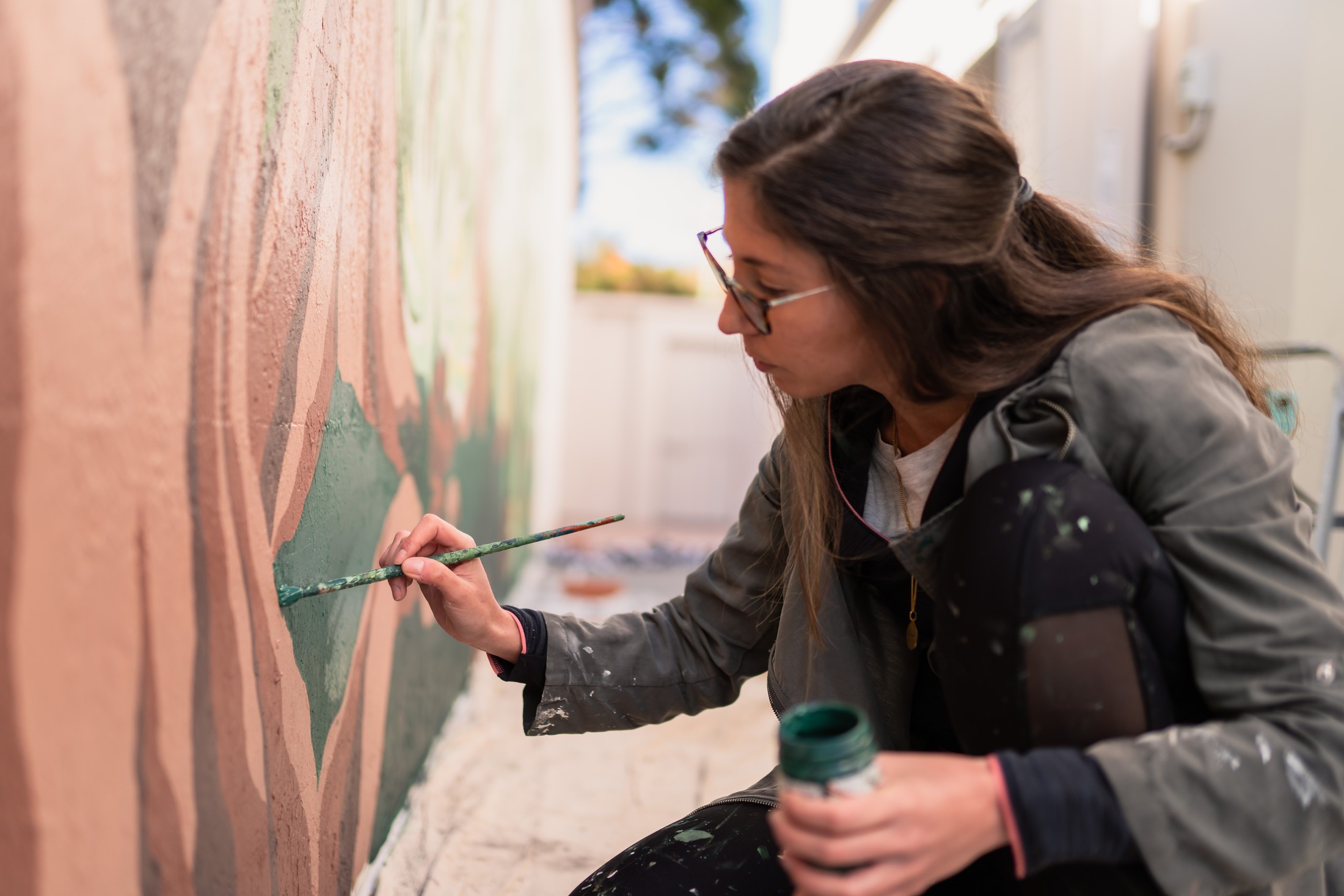 María Téllez pintando a mano un mural, pincel en mano